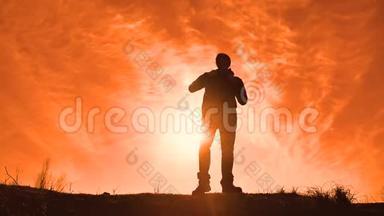 剪影阳光游客徒步旅行者背着背包从山顶欣赏日落景色。 徒步旅行者的剪影